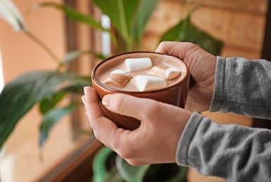 Photo of Woman holding cup of aromatic cacao with   marshmallows, closeup