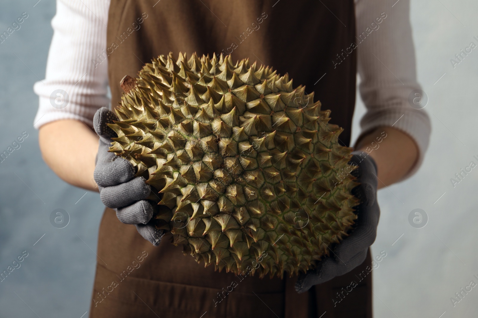 Photo of Woman with fresh ripe durian against blue background, closeup