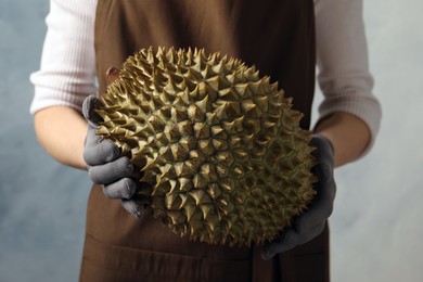 Photo of Woman with fresh ripe durian against blue background, closeup