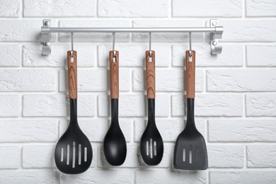 Photo of Rack with kitchen utensils hanging on white brick wall