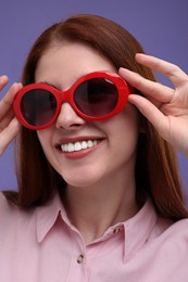 Photo of Portrait of smiling woman in sunglasses with freckles on purple background