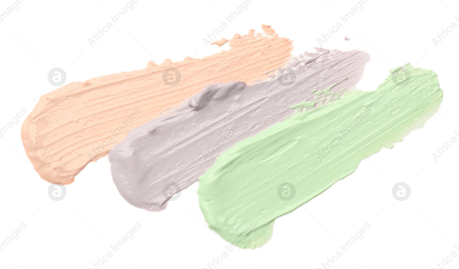 Photo of Strokes of pink, green and purple color correcting concealers isolated on white, top view