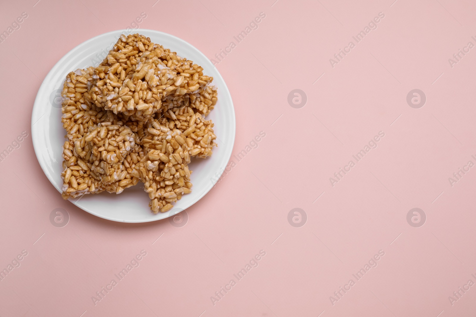 Photo of Puffed rice bars (kozinaki) on pale pink background, top view. Space for text