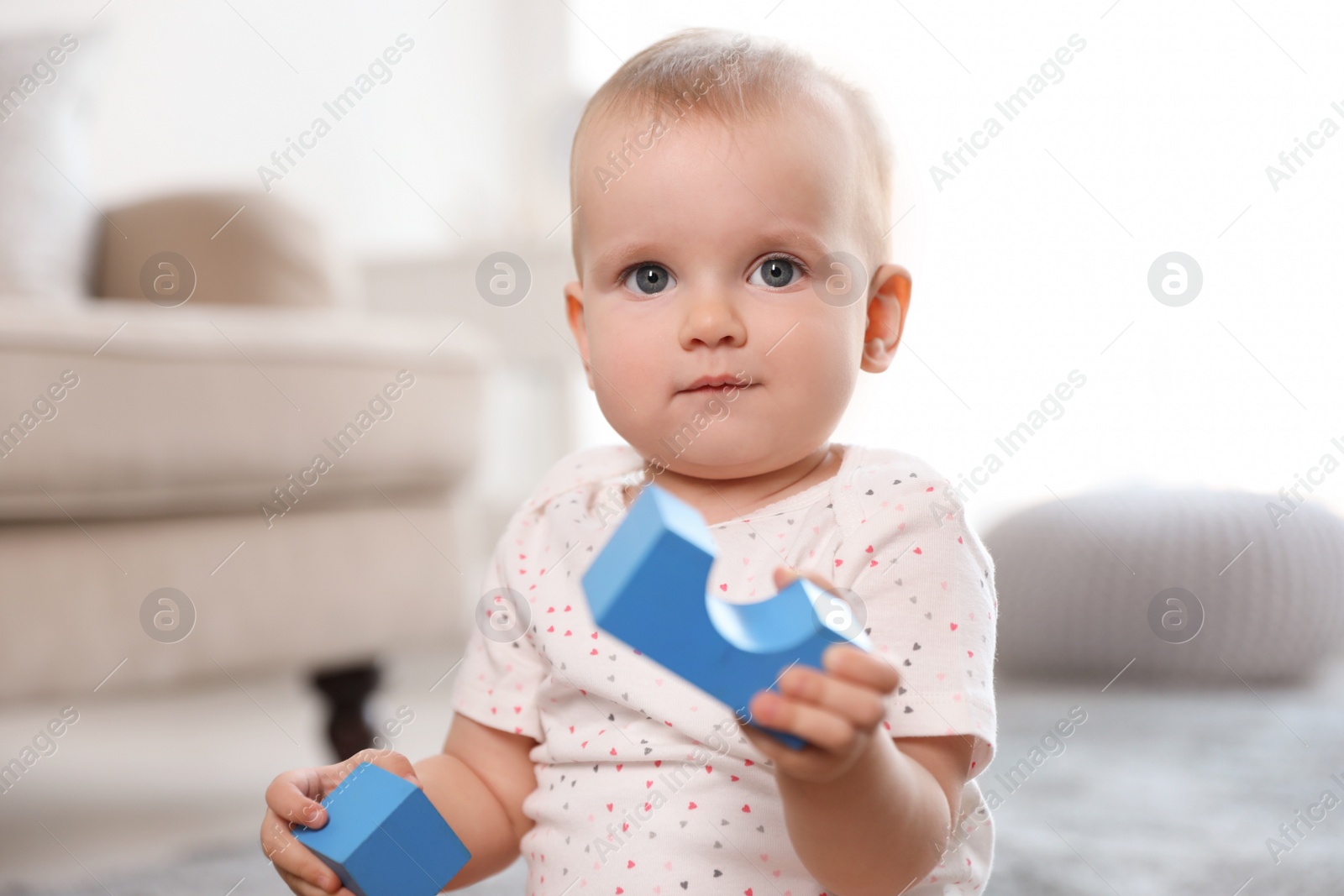 Photo of Cute baby girl playing with building blocks in room