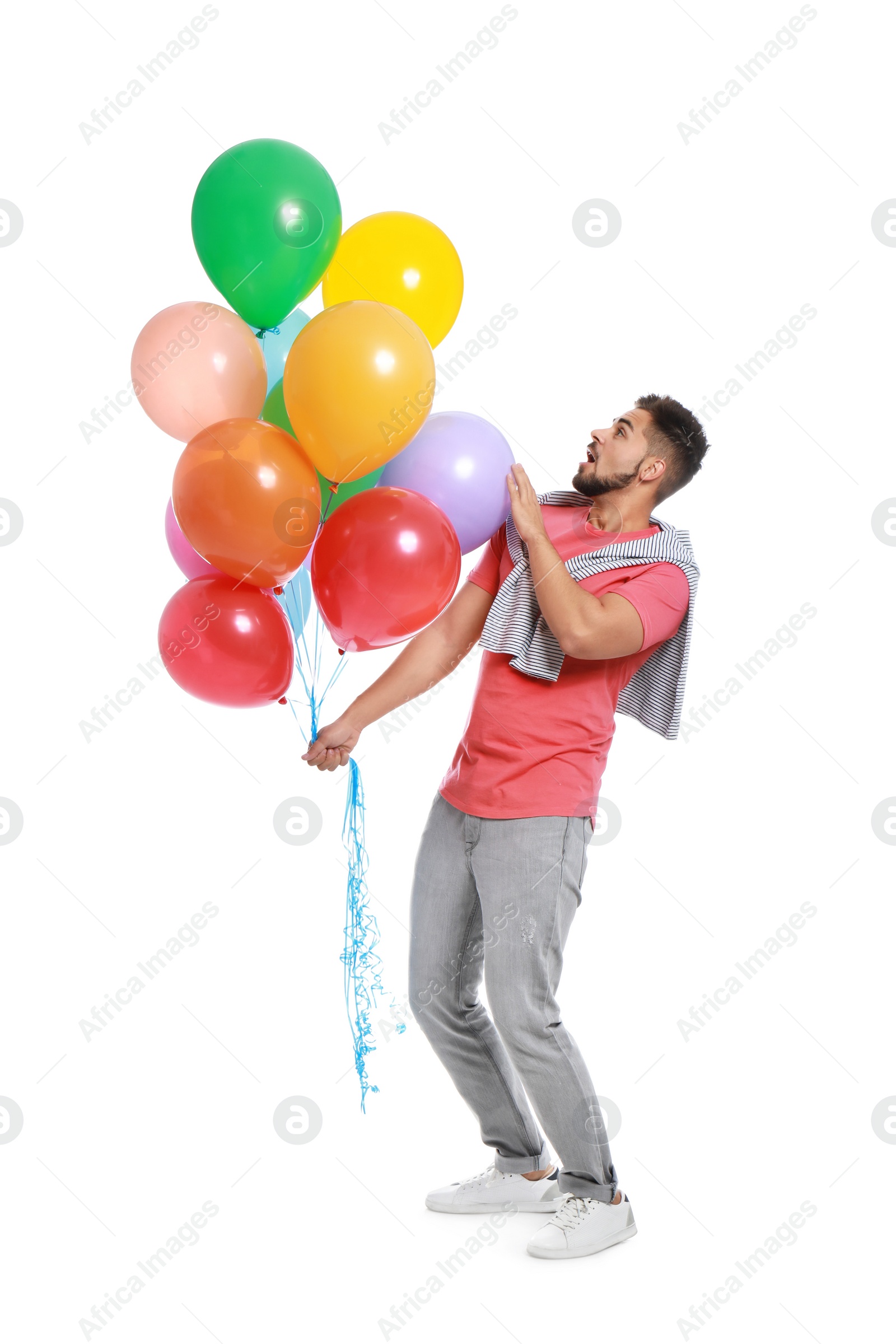 Photo of Emotional young man holding bunch of colorful balloons on white background