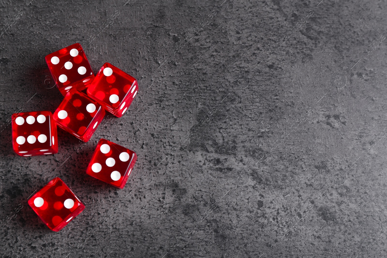 Photo of Many red game dices on grey textured table, flat lay. Space for text