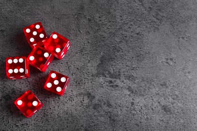 Photo of Many red game dices on grey textured table, flat lay. Space for text