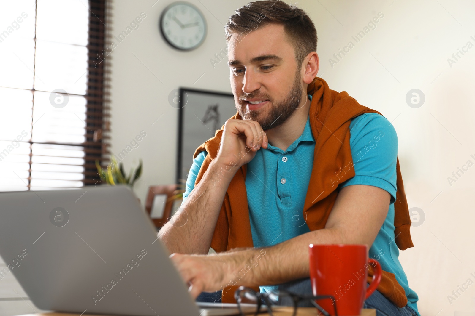 Photo of Young man using laptop at table indoors