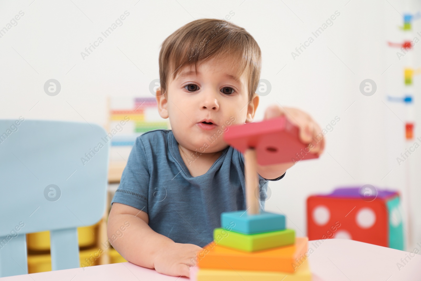 Photo of Little child playing with toy pyramid at table