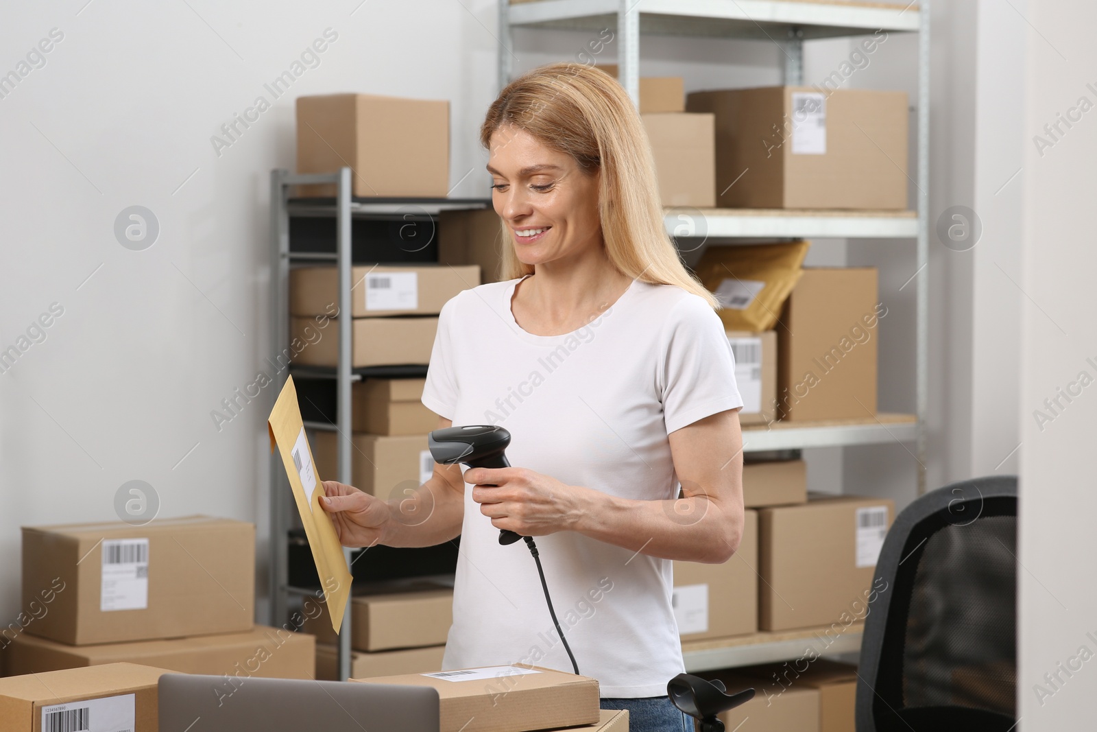 Photo of Seller with scanner reading parcel barcode at workplace. Online store