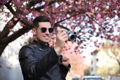 Happy male tourist with camera outdoors on spring day