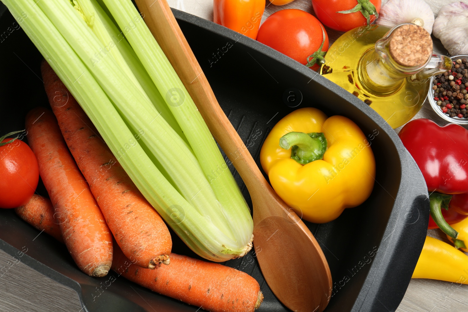 Photo of Black pot, spoon and fresh products on wooden table, top view