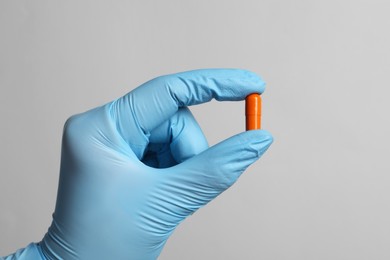 Photo of Doctor holding pill on grey background, closeup