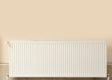 Photo of Modern heating radiator near closed windows indoors