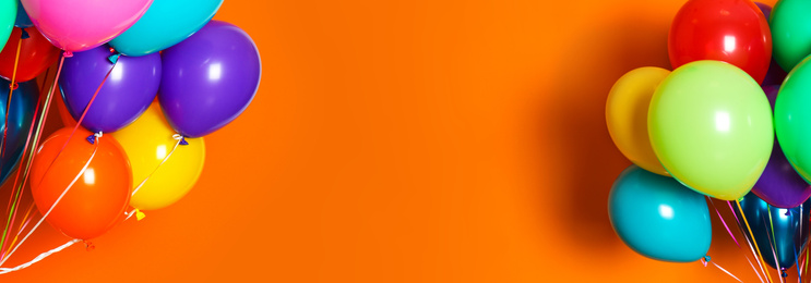 Image of Bunches of bright balloons on orange background, space for text. Banner design 