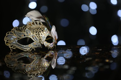 Beautiful carnival mask on table against blurred lights. Space for text