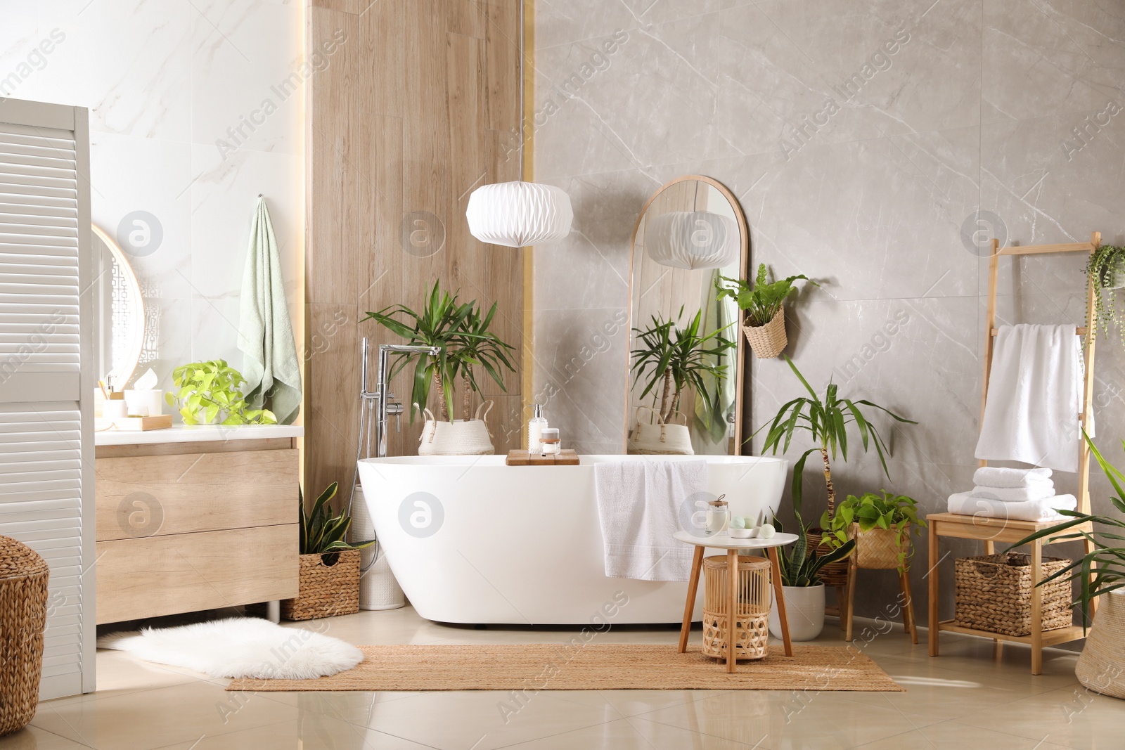 Photo of Modern white tub and beautiful green houseplants in bathroom. Interior design