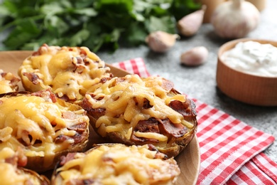 Photo of Plate of baked potatoes with cheese and bacon on table, closeup