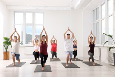 Photo of Group of people practicing yoga on mats indoors