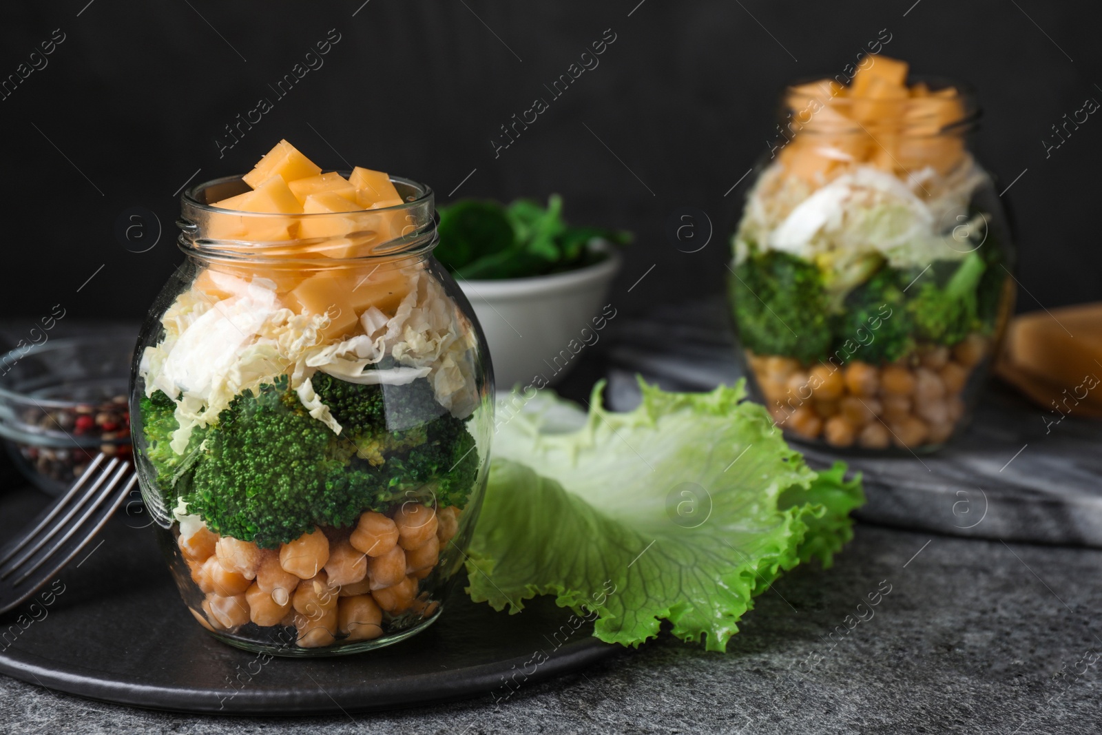 Photo of Healthy salad in glass jars on grey table