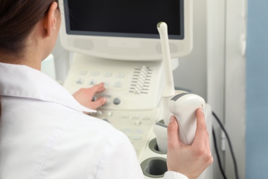 Professional sonographer using modern ultrasound machine in clinic, closeup