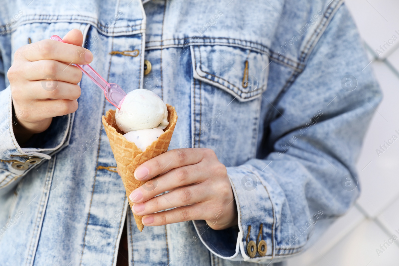 Photo of Woman eating delicious ice cream on light background, closeup