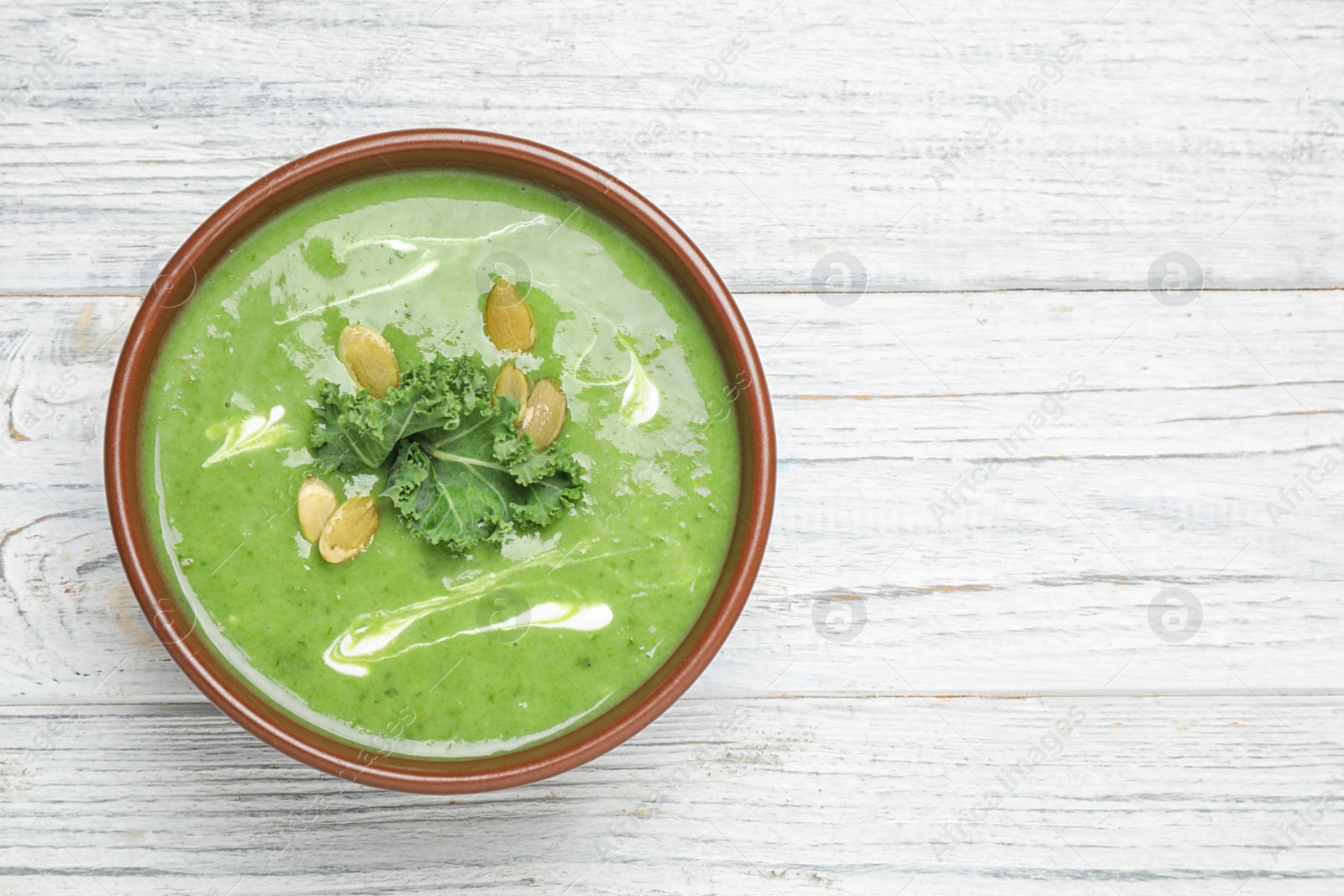 Photo of Tasty kale soup on white wooden table, top view. Space for text