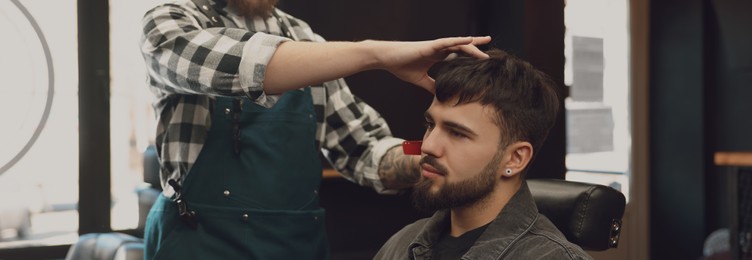 Professional hairdresser working with bearded client in barbershop. Banner design