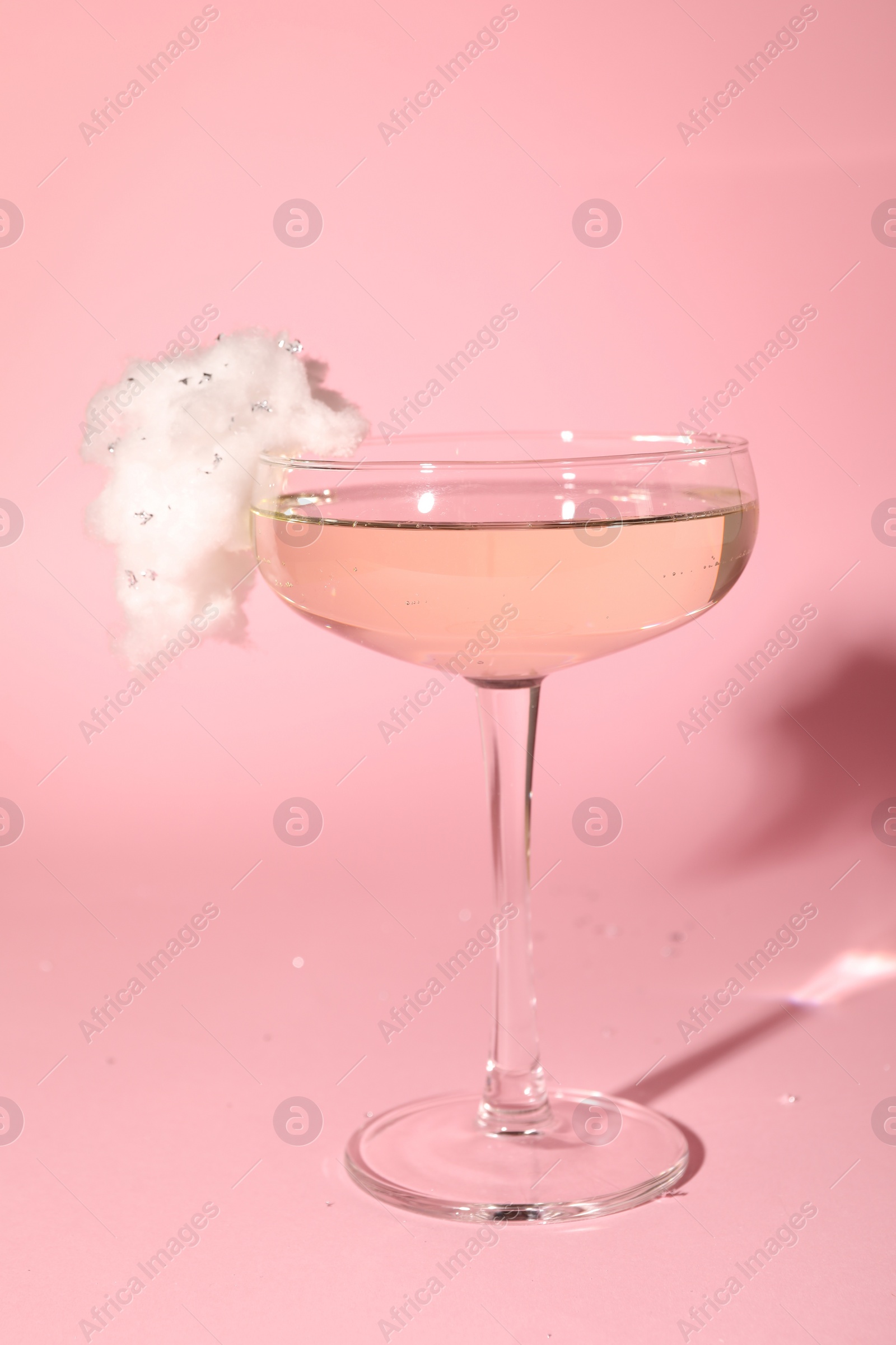 Photo of Tasty cocktail in glass decorated with cotton candy on pink background