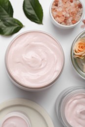 Body cream and other cosmetic products with rose on white background, top view