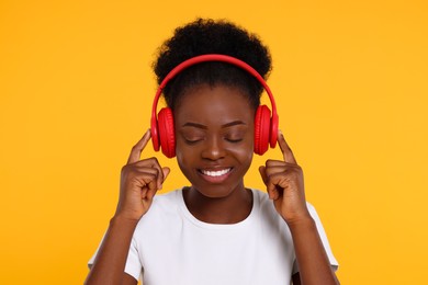 Photo of Young woman in headphones enjoying music on orange background