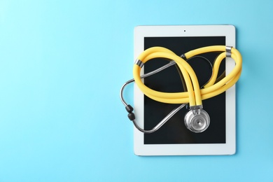 Stethoscope and tablet on color background, top view. Medical equipment