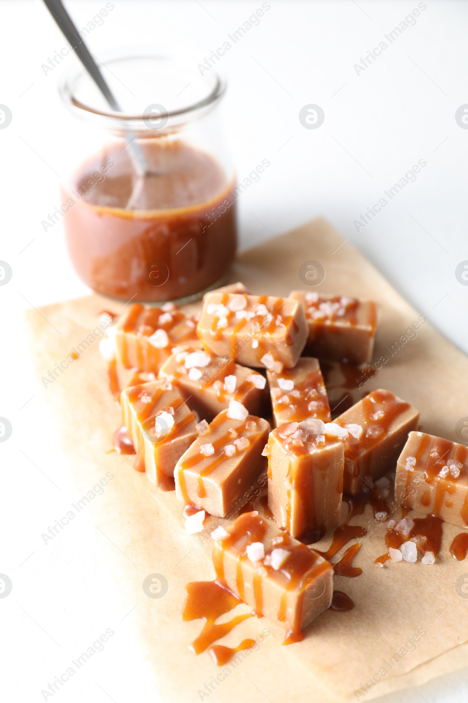 Photo of Tasty candies, caramel sauce and salt on white table