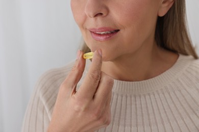 Woman taking vitamin pill at home, closeup