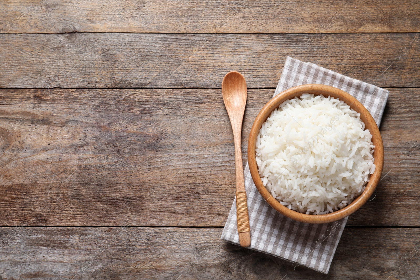 Photo of Bowl of delicious rice on wooden table, top view with space for text