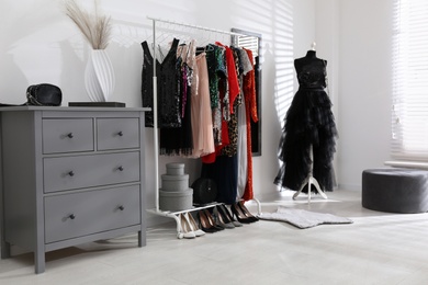 Photo of Rack with collection of beautiful festive clothes in stylish room interior