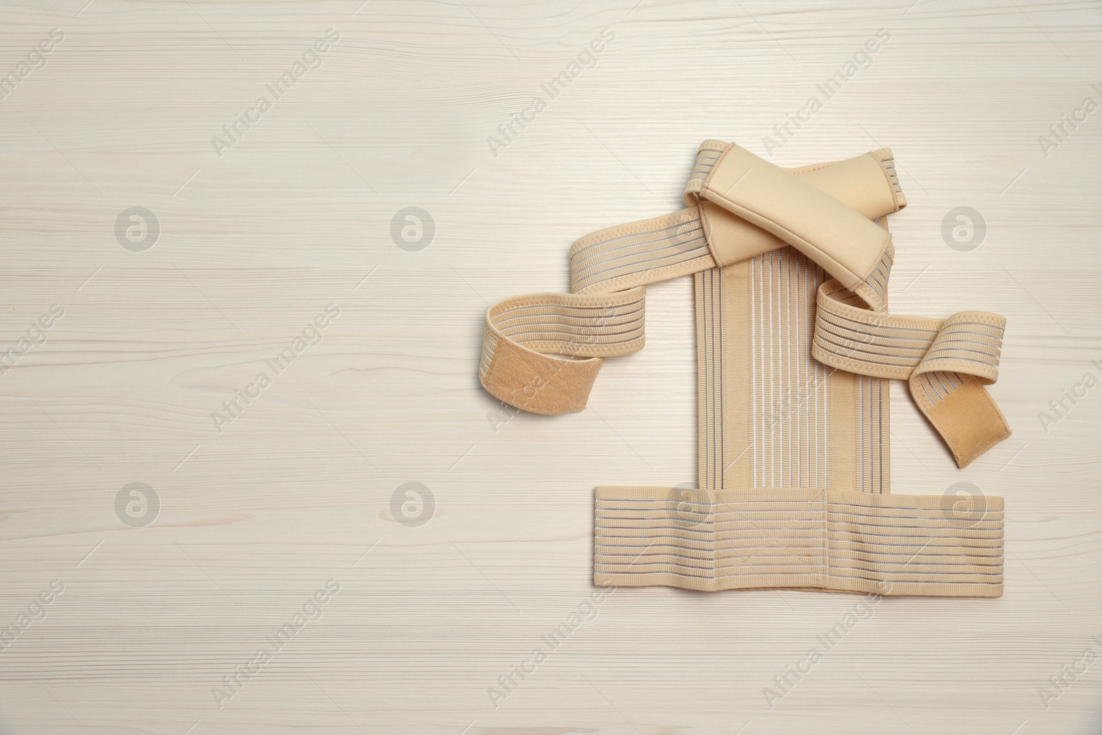 Photo of Beige posture corrector on white wooden table, top view. Space for text