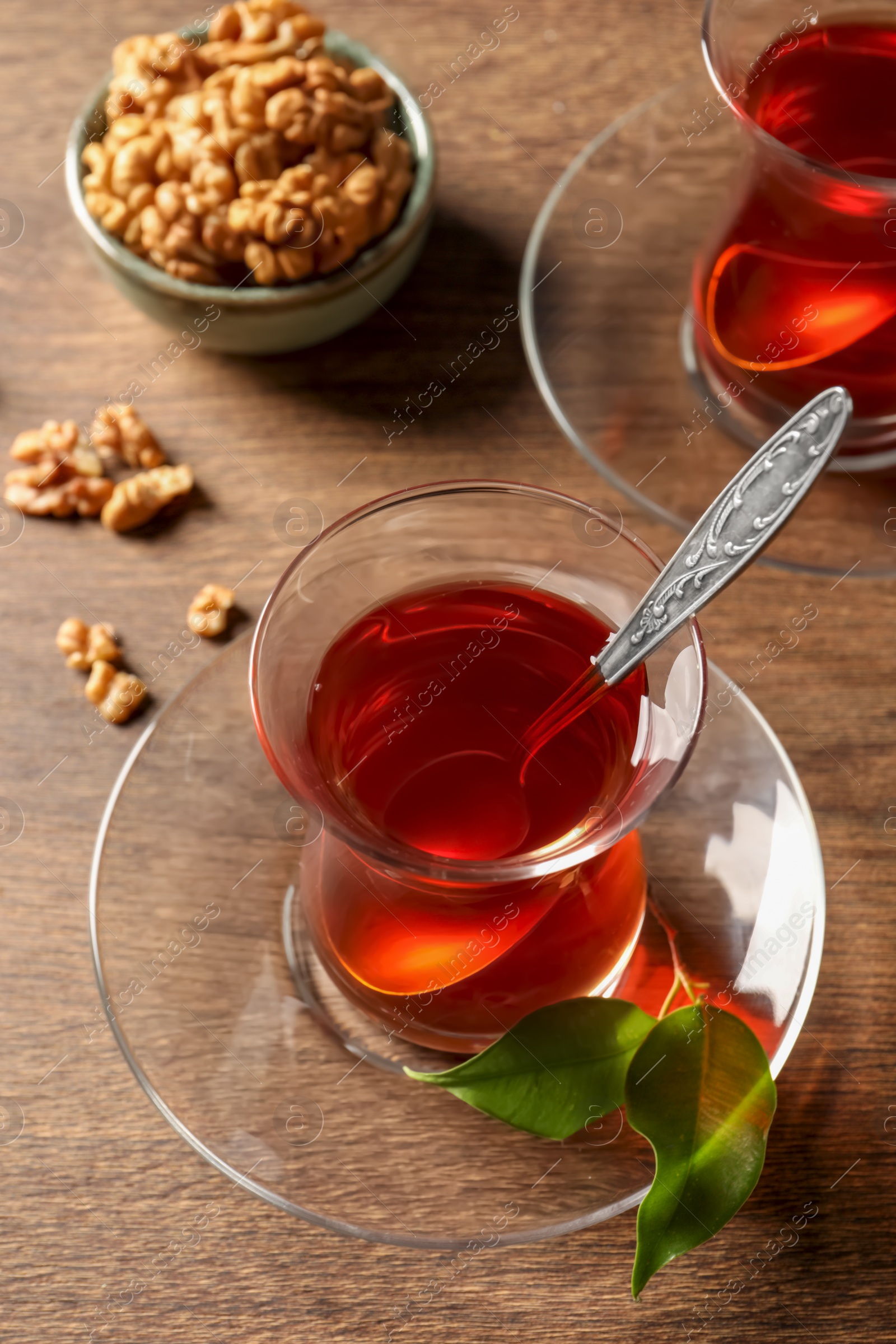Photo of Glasses of traditional Turkish tea and walnuts on wooden table, above view