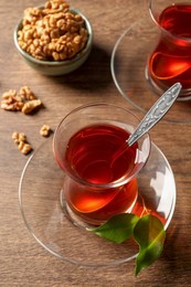 Glasses of traditional Turkish tea and walnuts on wooden table, above view