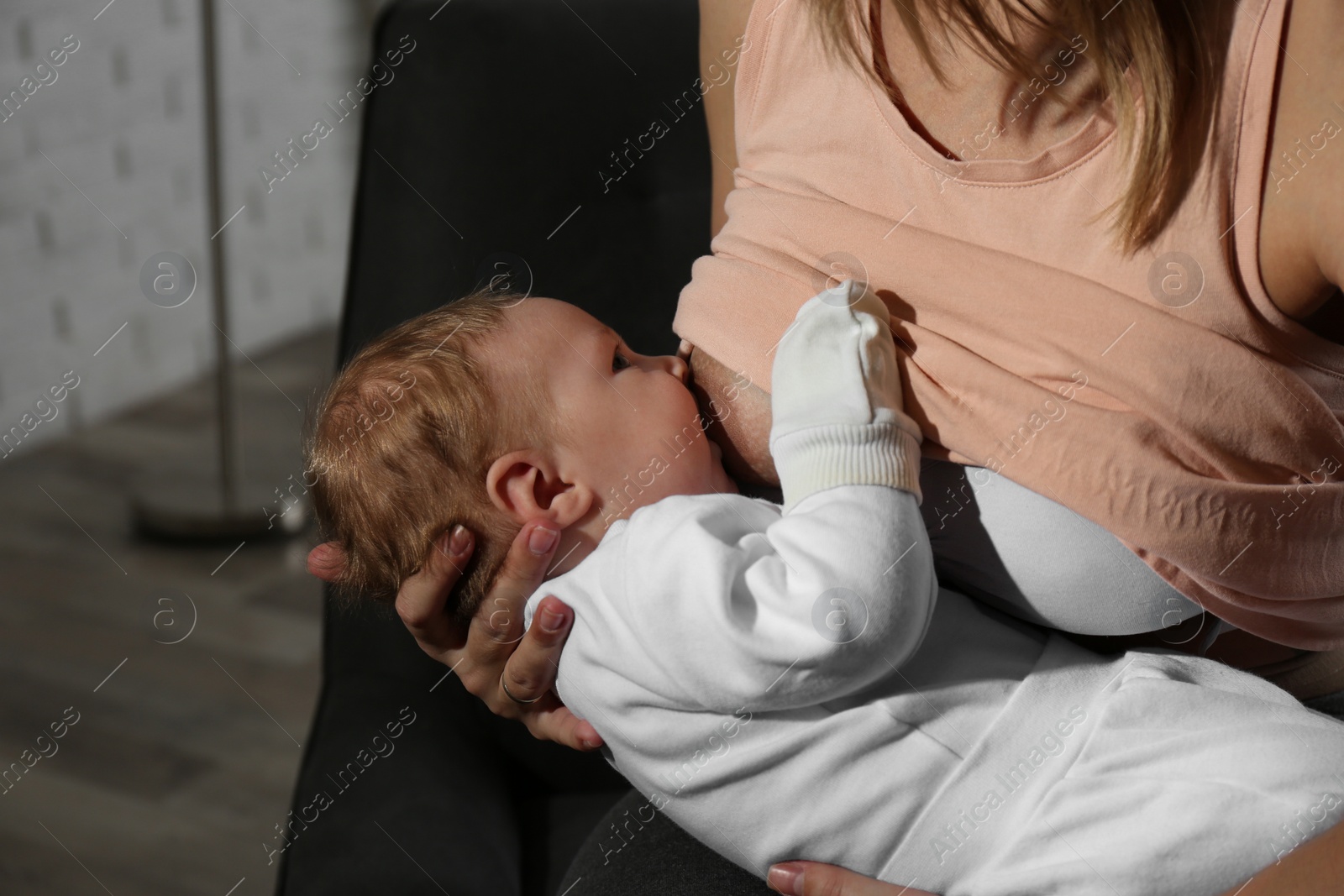 Photo of Young woman breast feeding her little baby at home, closeup