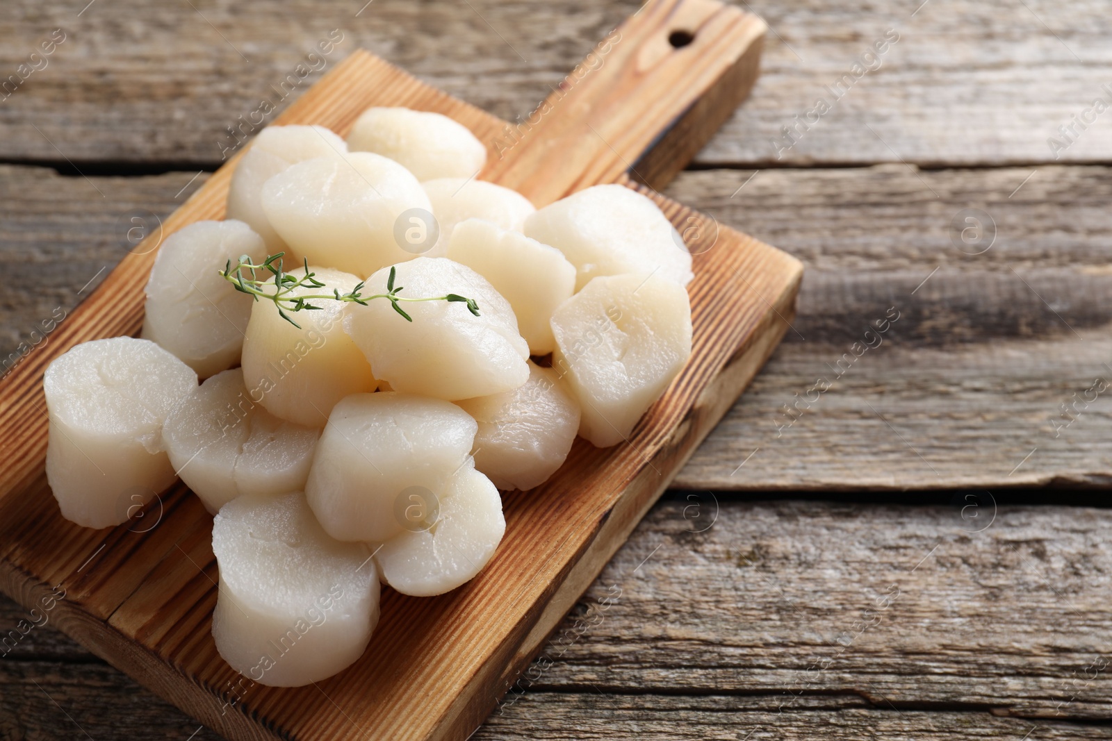 Photo of Fresh raw scallops and thyme on wooden table. Space for text