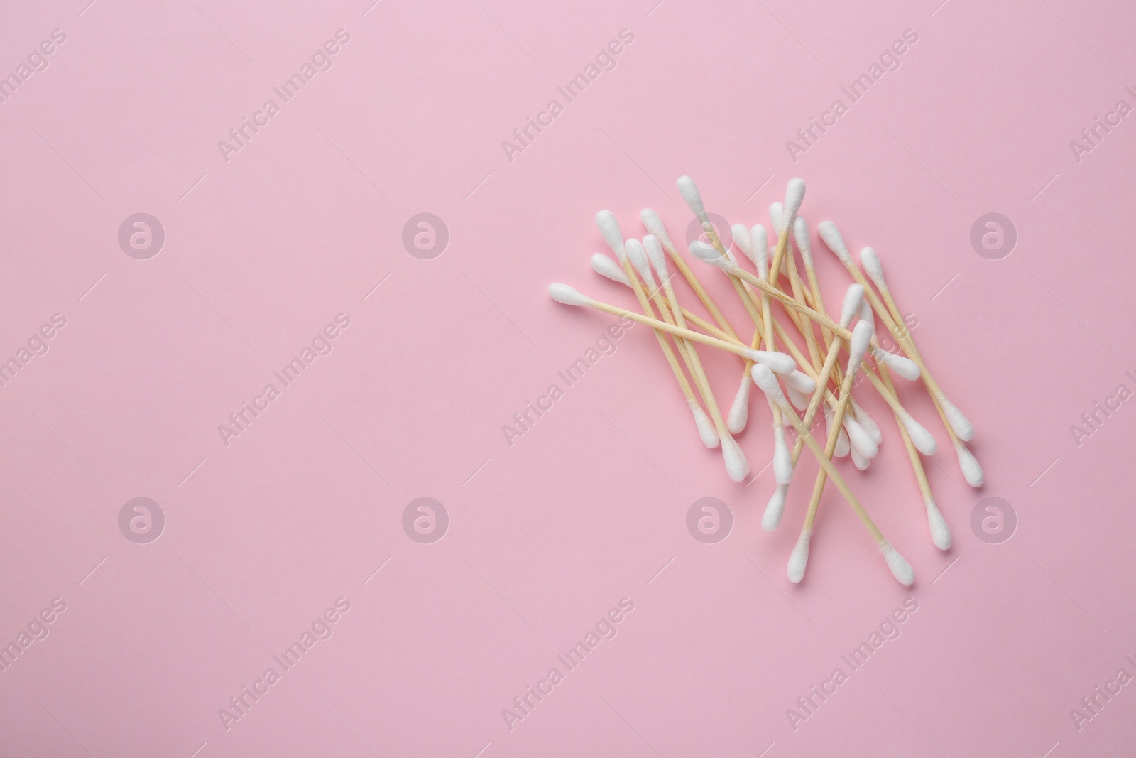 Photo of Heap of wooden cotton buds on pink background, flat lay. Space for text