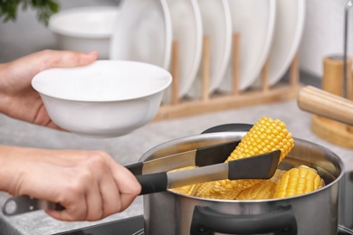 Woman preparing corn in stewpot on stove, closeup