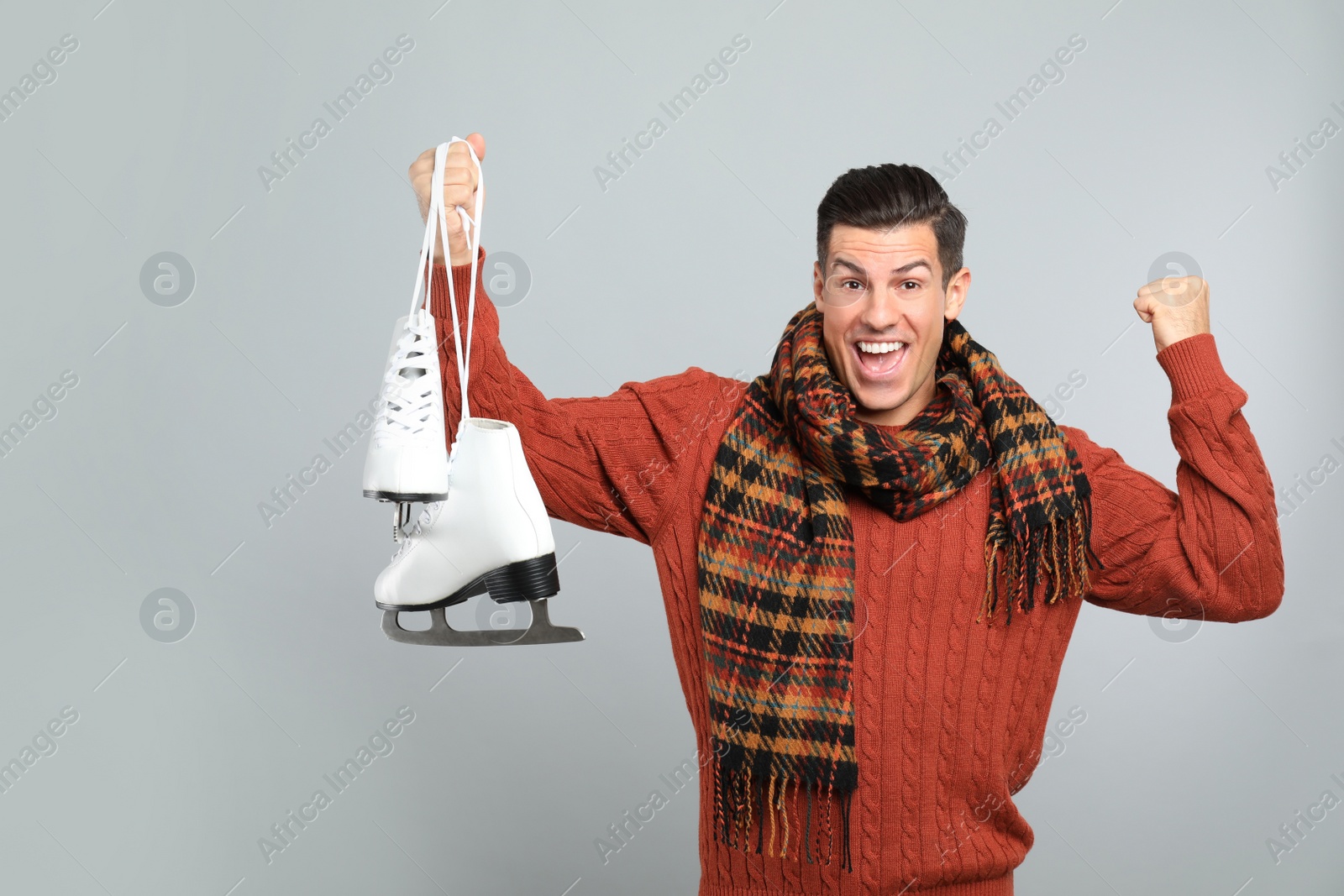 Photo of Emotional man with ice skates on grey background