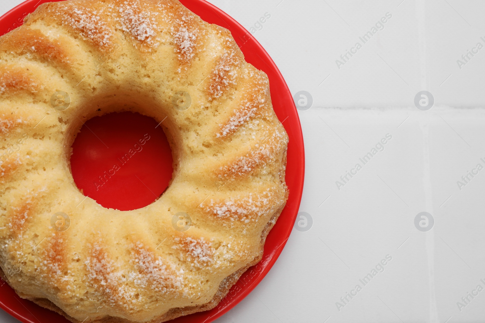 Photo of Delicious freshly baked sponge cake on white tiled table, top view. Space for text