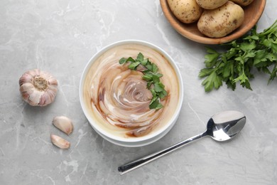 Delicious cream soup with soy sauce and parsley served on grey marble table, flat lay