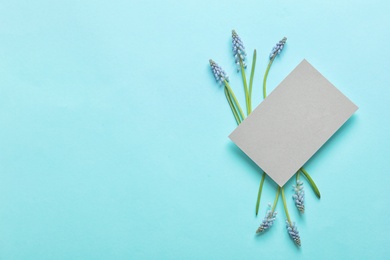 Beautiful spring muscari flowers and card on color background, top view with space for text