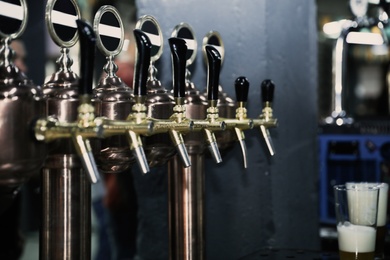 Photo of New modern beer taps on bar counter in pub