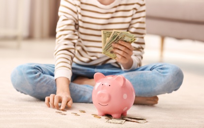 Photo of Teen girl with piggy bank and money at home, closeup