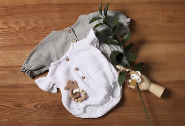 Photo of Flat lay composition with children's clothes, toys and pacifier on wooden table